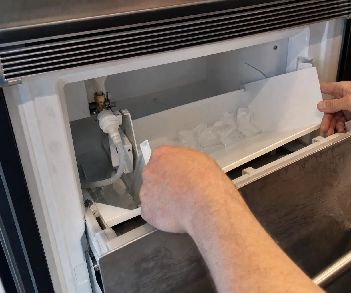 A refrigerated drawer pulled open on its runners, hands taking the bin out of it.