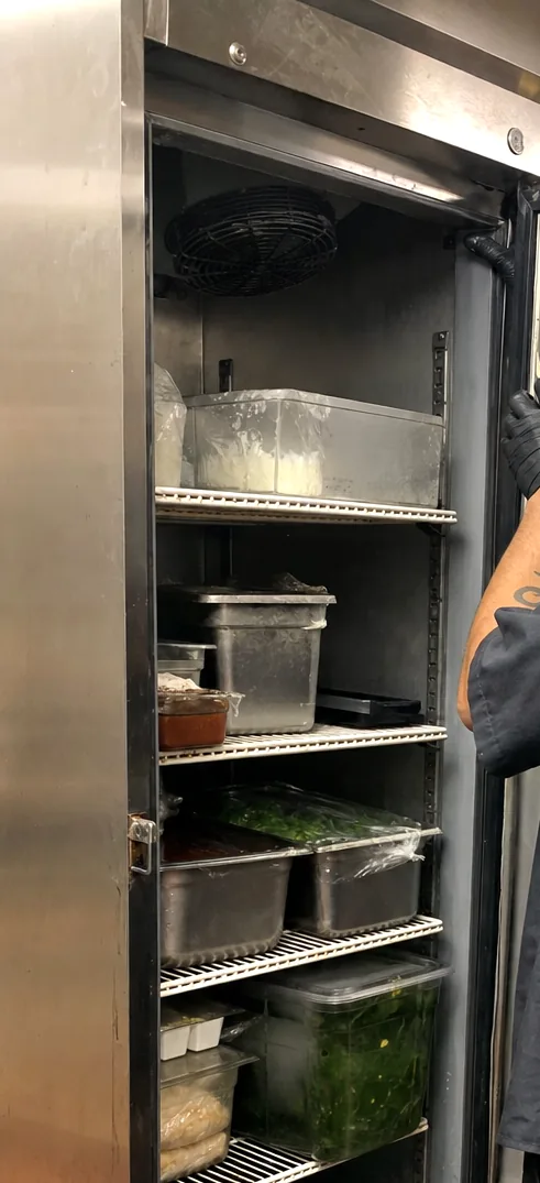 The upper corner of an open refrigerator door, the hinge line and the magnetic gasket running along the frame.