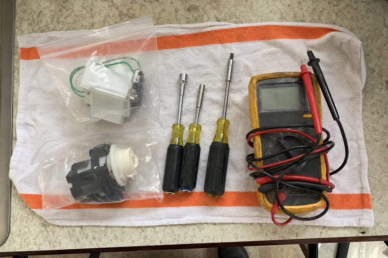 Replacement components in sealed bags laid beside nut drivers on a folded kitchen towel.
